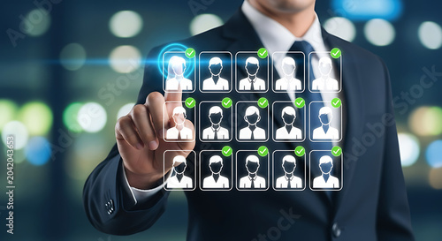 Business professional selecting diverse team members on digital interface in modern office