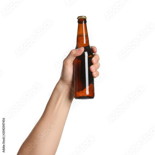 Person holding amber glass beer bottle with metal cap, product ready for consumption on transparent background.
