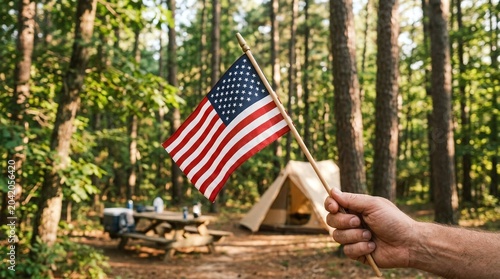 Hand holding a small american flag in a forest campsite