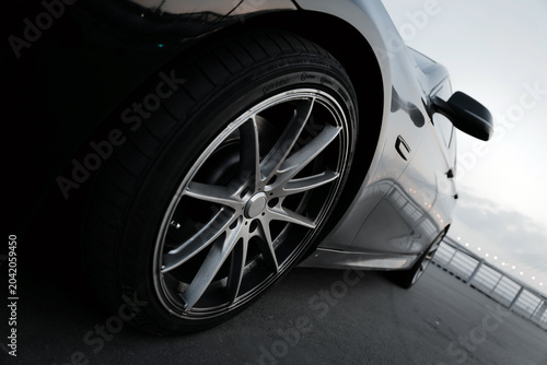 A black BMW 5 Series car against the backdrop of the Yacht Bridge in St. Petersburg at sunset.