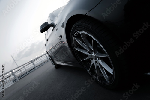 A black BMW 5 Series car against the backdrop of the Yacht Bridge in St. Petersburg at sunset.