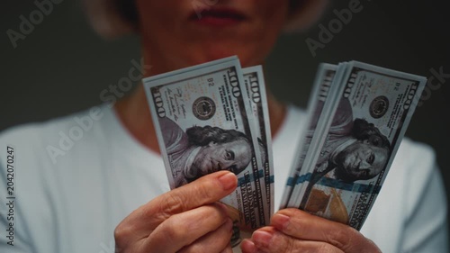 Old Caucasian woman counts the cash one hundred in hands, banknotes. Senior female holds paper money USD dollars in palms, with money deficit. Utility Bills Payment earnings. Elderly lady counting.