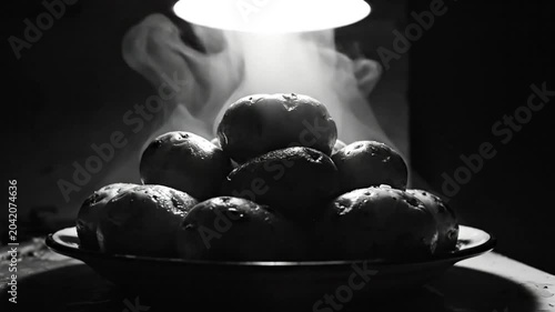 Steaming potatoes under a bright light in a dark room creating a still life food photography shot