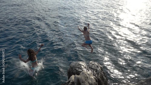 Little beautiful girl jumping from stone to sea