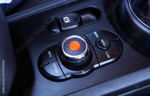 Modern car multimedia switch, multimedia controls. Sophisticated center console with large rotary knob red accent and buttons labeled menu media option back. It showcases premium vehicle interior adva