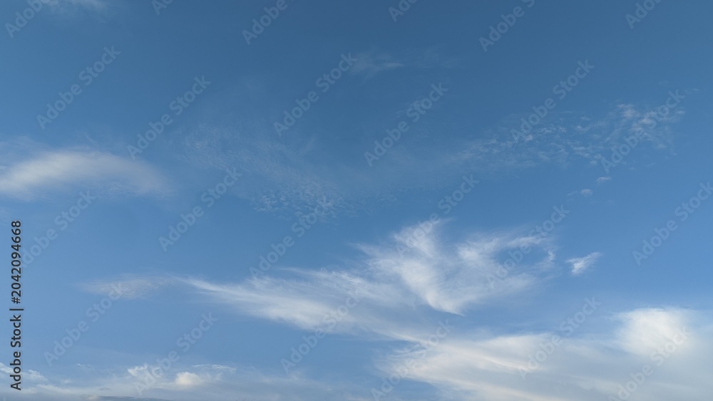 Fototapeta premium Clear blue sky with light white wispy clouds. natural background texture for sky replacement, background, wallpaper, presentation backdrop, graphic design with ample copy space.