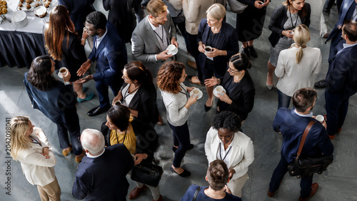 Professionals gather in a large hall to network and socialize during a busy corporate event held in an urban conference center, creating a collaborative environment for new business relationships.