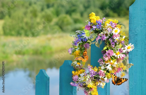 summer background. wreath of colorful flowers on blue wooden fence outdoor. Floral crown, symbol of Summer Solstice Day, Midsummer, Litha, Ligo holidays. slavic tradition. wiccan ritual. copy space