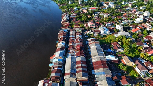 Fotografía Aerial view of a densely populated riverside town with colorful buildings and lush greenery