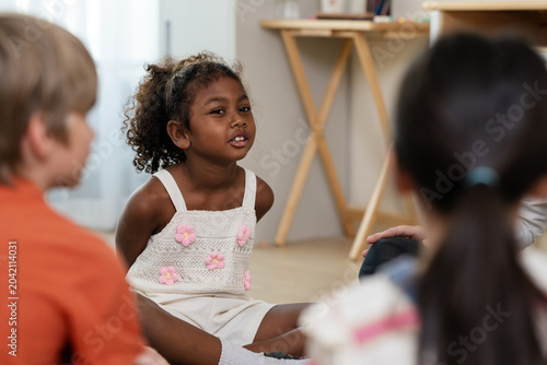 Quadro su tela Young girl talks with multicultural classmate during classroom circle discussion