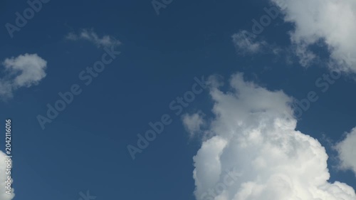 Puffy clouds moving across blue sky timelapse