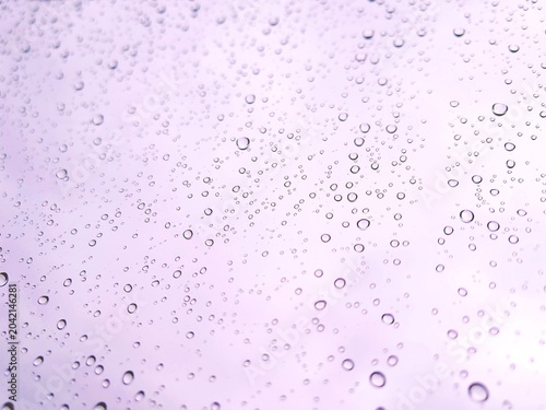Rain drops on a light purple surface macro background