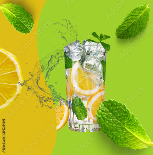 Refreshing mojito cocktail with fresh mint and lemon slices on green background
