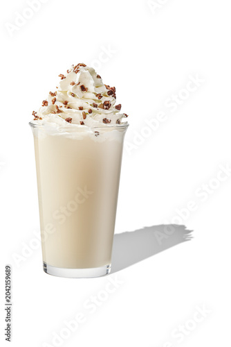 Eye level shot of creamy milkshake drink topped with whipped cream and crushed nuts, isolated.