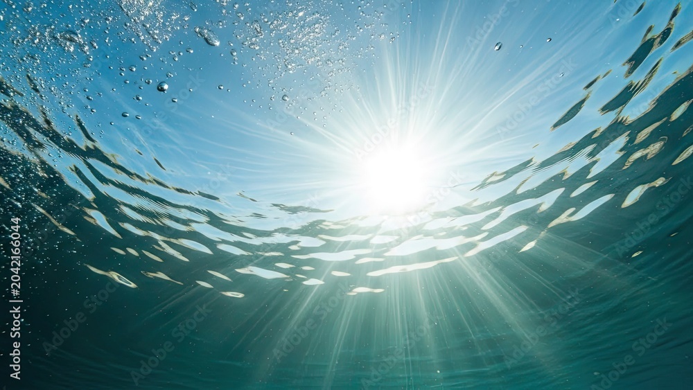 Obraz premium Sunlight rays through blue ocean water surface.