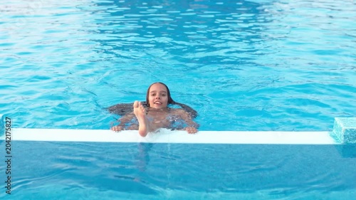 Girl in leopard swimsuit playing in the pool under the summer sun