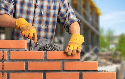 Construction workers building walls with brick blocks.