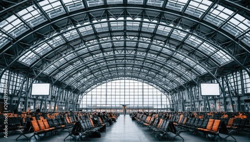 Vast, modern arched hall with rows of empty seats under a steel and glass roof