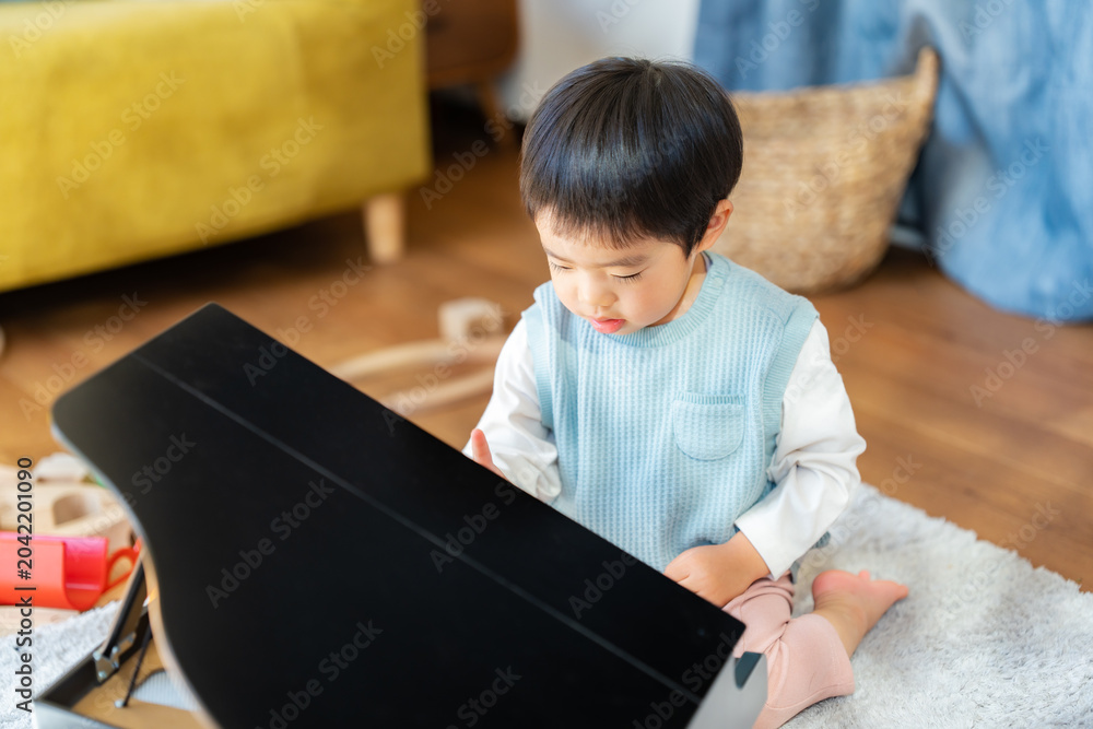 Fotografija リビングでおもちゃのピアノを弾く3歳の男の子