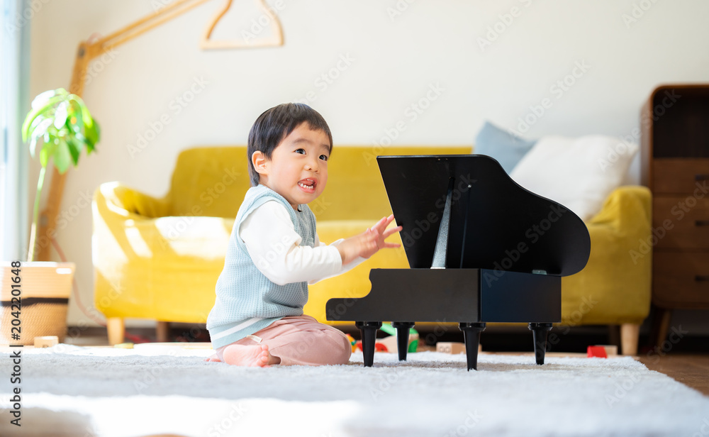 Φωτογραφία リビングでおもちゃのピアノを弾く3歳の男の子