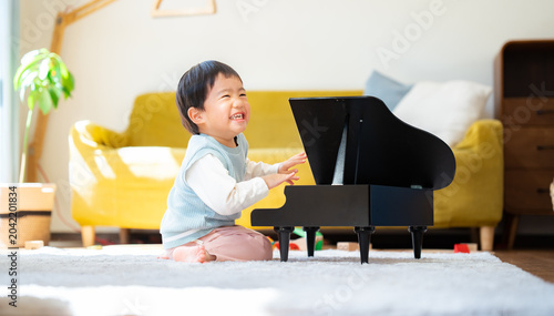Foto リビングでおもちゃのピアノを弾く3歳の男の子