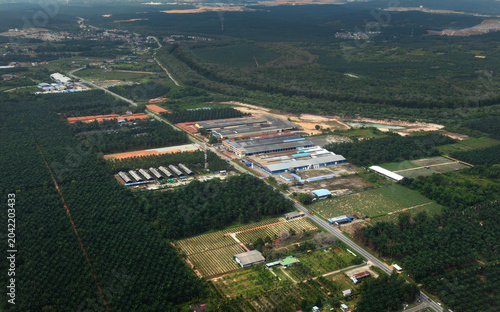 Aerial view of oil palm plantations and industrial facilities on the outskirts of Kuala Lumpur, Malaysia, showing agriculture and land development.