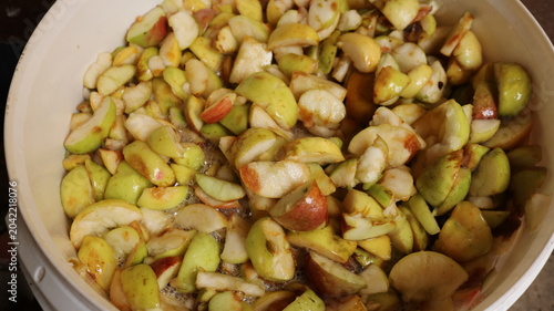 Sliced ​​yellow and red apples in a white plastic bucket, making homemade juice, puree, or alcohol from the apple harvest, preparing an apple ingredient for infusing a drink at home