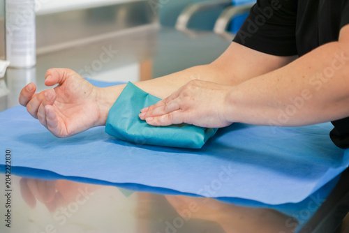Tableau sur toile Medical professional applying a sterile green wrap over a patient arm in a clean