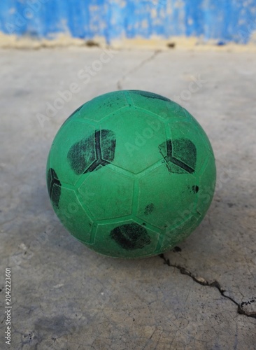 Green plastic ball on cement floor, children's toy