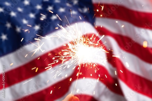 Hand holding a sparkler and American Flag