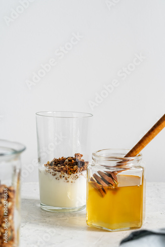 Healthy granola breakfast in glass on light background, homemade granola, yogurt, organic honey