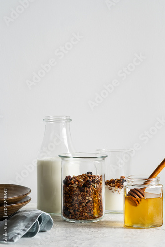 Healthy granola breakfast on light background, homemade granola, yogurt, honey, and bottle of milk