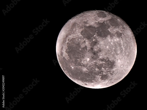 Close-up shot of a full moon with craters and gray surface details against a black background.