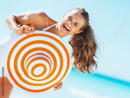 happy young woman in swimsuit with beach hat having