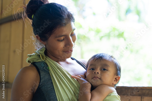 Foto Indigenous mother tenderly holding baby in sling