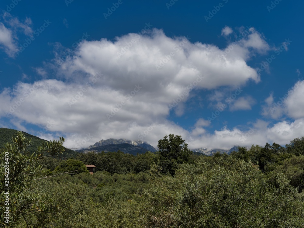 Fototapeta premium Wide view of green landscape with mountains and clouds during daytime in a rural area