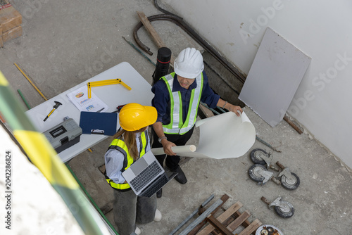 Принти на полотні Professional engineer and worker stand in construction site holding blueprint we