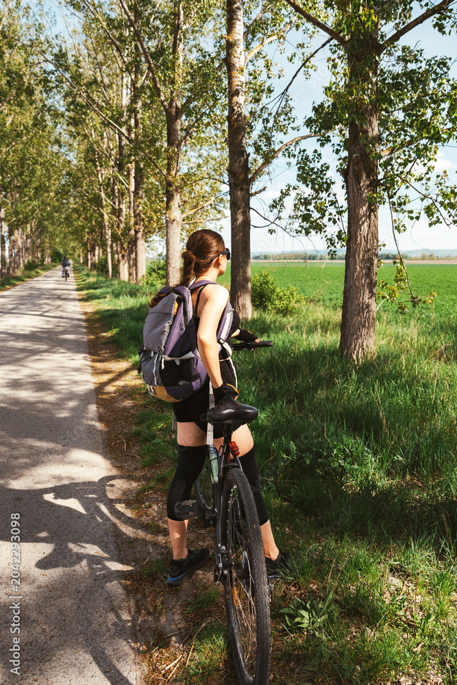 Obraz premium Active woman enjoying outdoor wellness lifestyle through cycling in countryside.