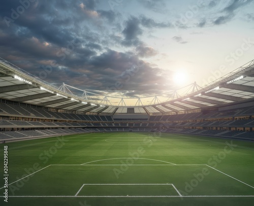 Wide angle view of an empty soccer stadium with green field under a dramatic sunset sky.
