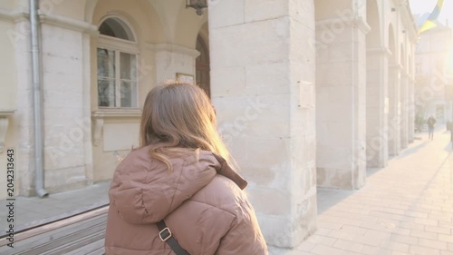 Young woman walking in European city street at sunrise