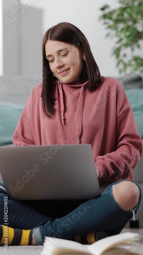 Woman sits on floor with a laptop, studying and enjoying her time in a cozy space.