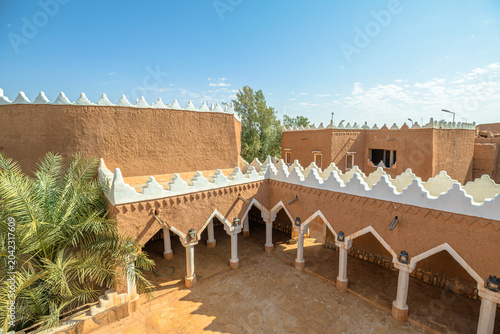 Ushaiqer Heritage Village interior featuring Najdi mud-brick architecture with white columns, decorative arches and textured adobe walls preserving Saudi Arabia's cultural past of Arabs