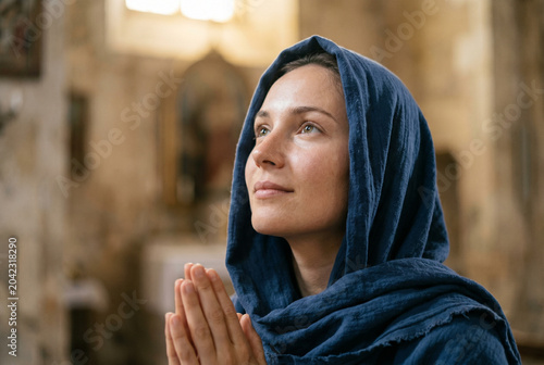 Woman praying with closed eyes in a church with natural light  