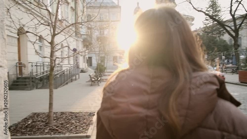 Young woman walking in European city street at sunrise