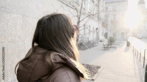 Young woman walking in European city street at sunrise