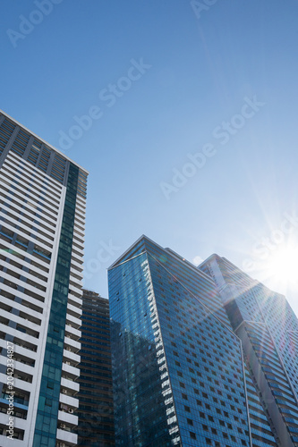 Modern high-rise residential buildings with glass facades against a clear blue sky.