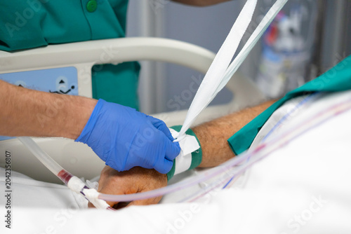 Foto Healthcare worker restraining patient arm with medical device