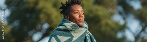 Woman wrapped in blanket gazing into distance outdoors