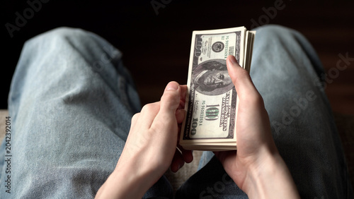 Tableau sur toile A young man holds a stack of cash in his hands
