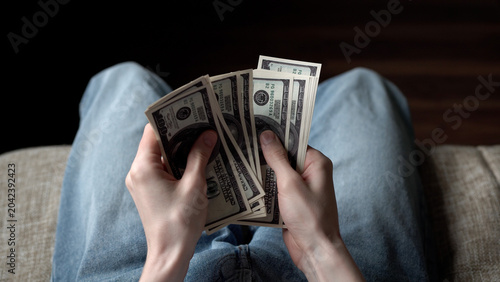 Canvastavla A man is sitting on a couch, holding several stacks of cash